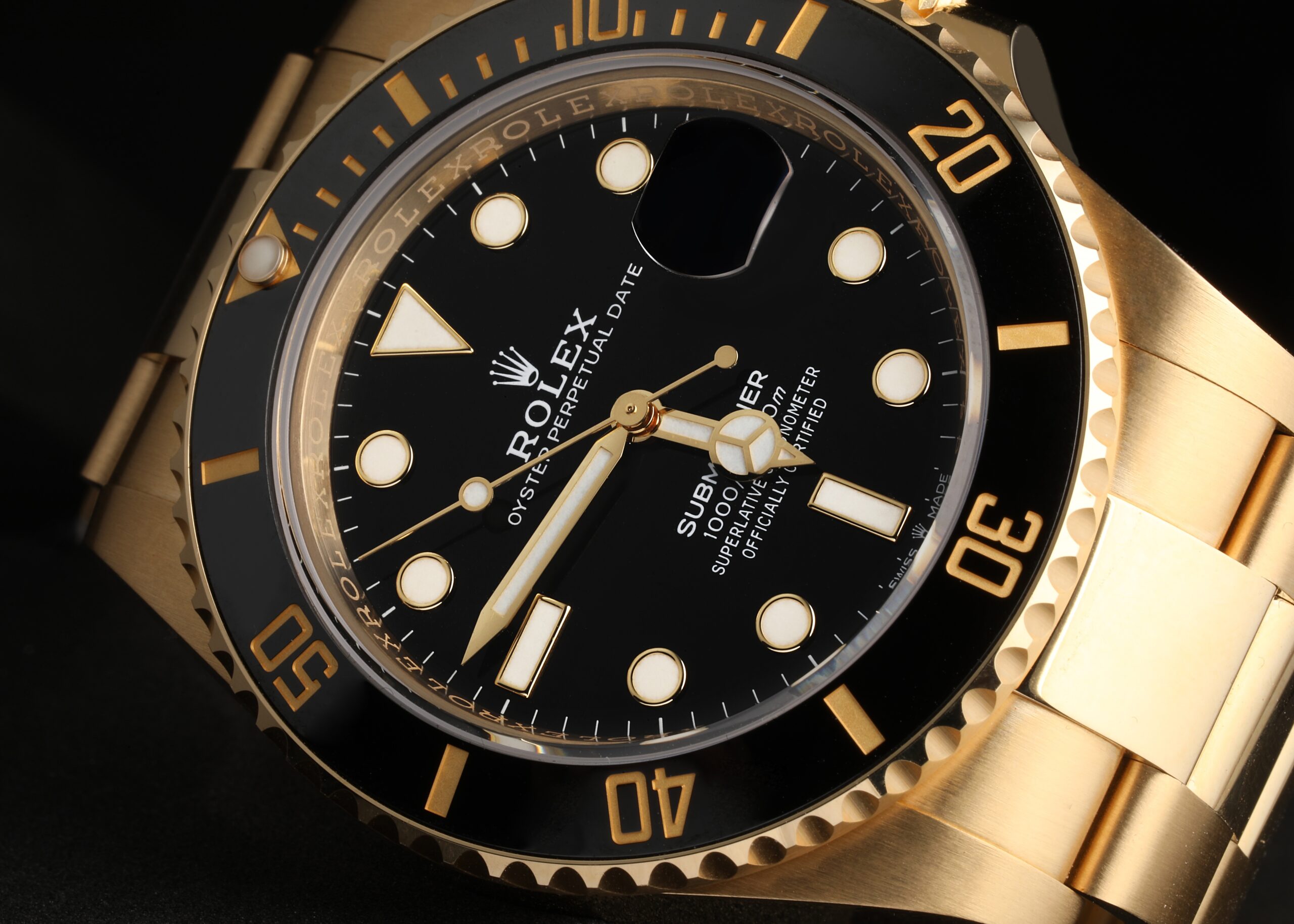 Macro side view of an 18k yellow gold Rolex Submariner dial showing sharp text, luminous hour markers, and clean hands.
