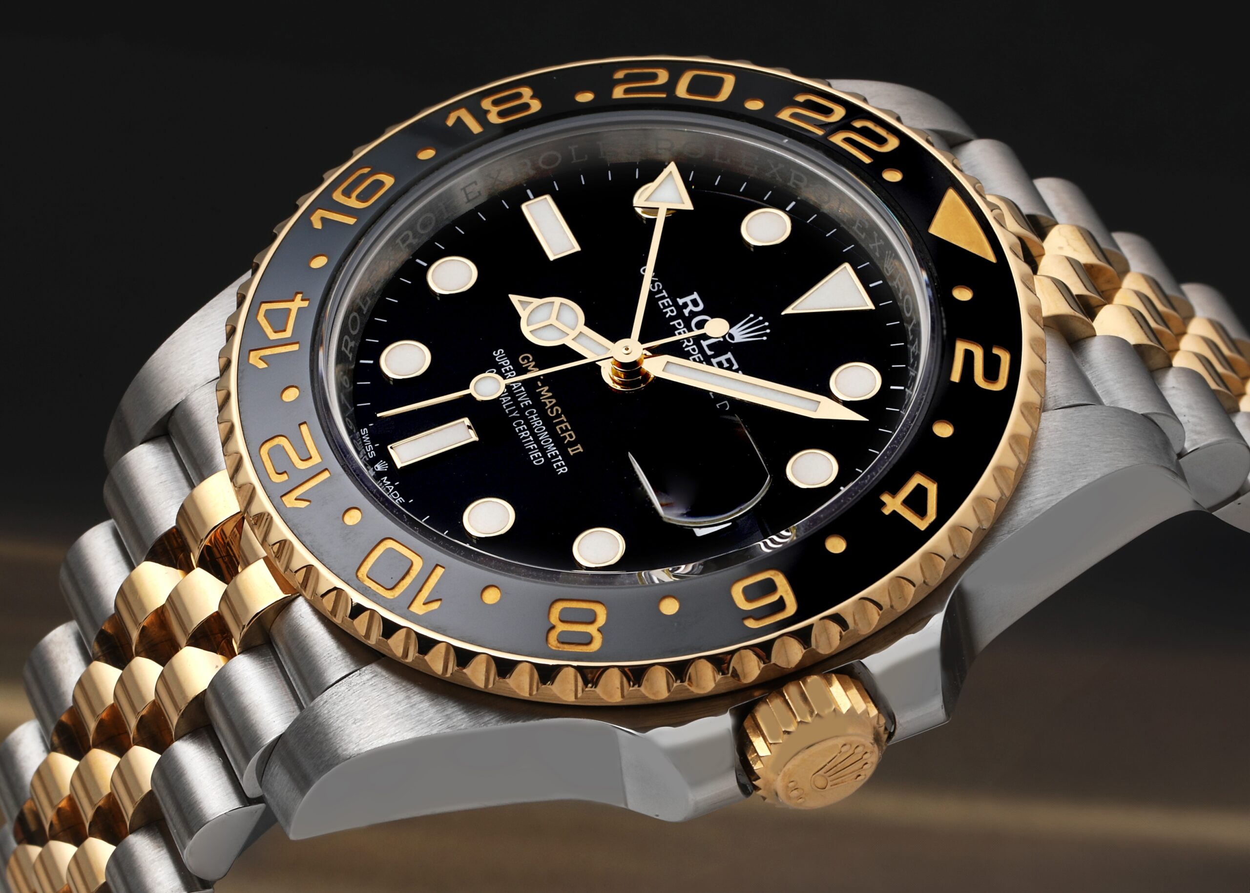 A detailed close-up of a two-tone Rolex GMT-Master II, showcasing its iconic black and grey bezel and the advanced Caliber 3285 movement that powers it.