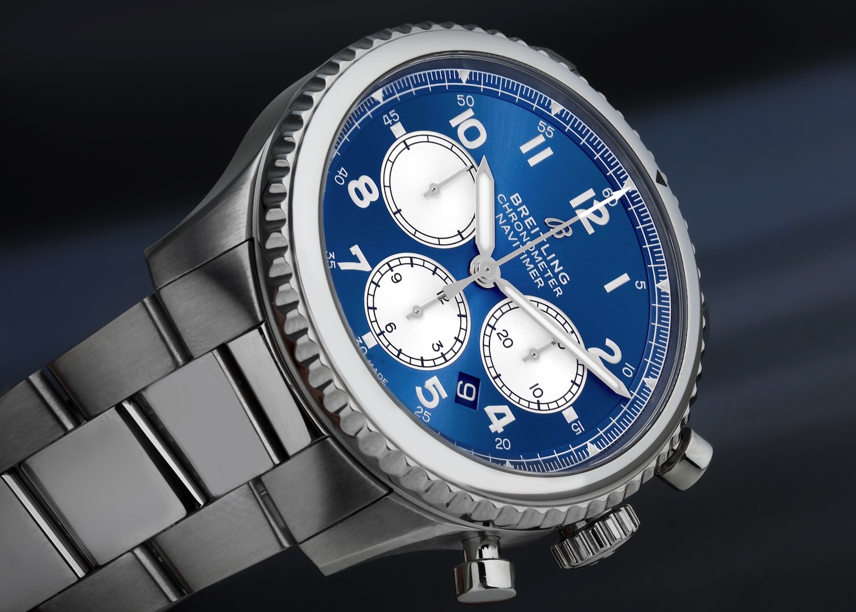  A close-up of a Breitling Aviator 8 B01 Chronograph with a vibrant sunray blue dial, contrasting white subdials, and a polished bezel with a single red pointer.