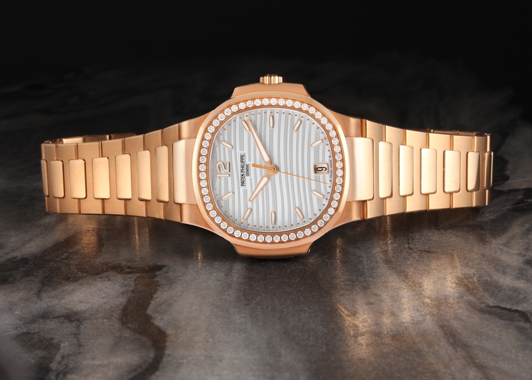 A Patek Philippe Nautilus 7118 in 18k rose gold, lying flat to showcase its iconic porthole-shaped case, brilliant-cut diamond bezel, and silvery-white dial with a horizontal embossed pattern.