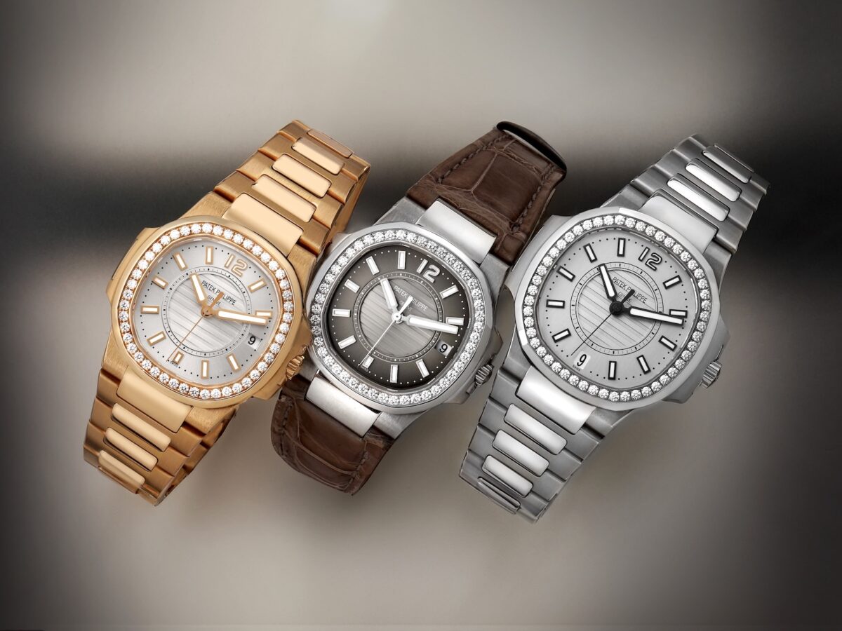 A lineup of three Patek Philippe Nautilus ladies watches. Left: Rose gold with white dial and bracelet. Center: White gold with dark grey dial and brown leather strap. Right: Stainless steel with white dial and bracelet. All feature diamond bezels.