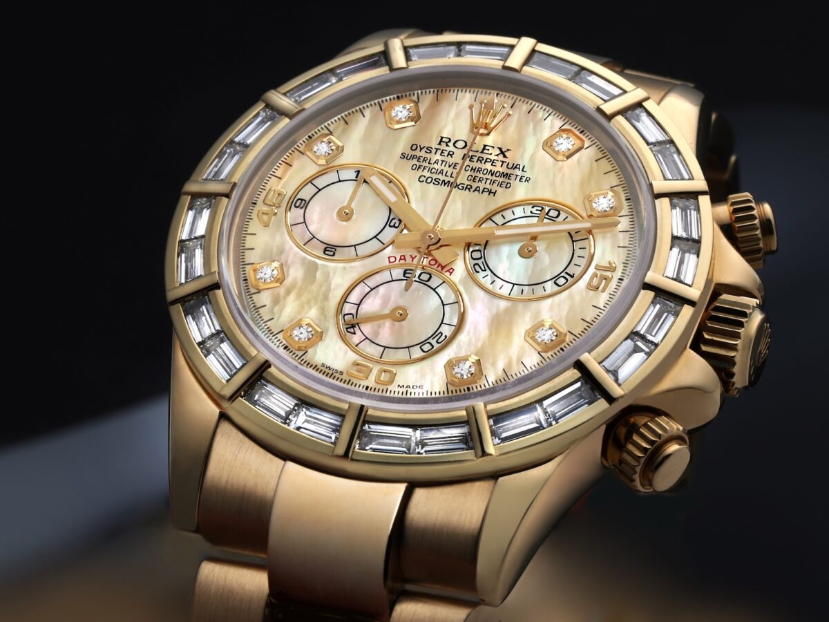 Macro view of a Rolex Cosmograph Daytona in 18k yellow gold featuring a factory-set baguette diamond bezel and white mother of pearl dial.