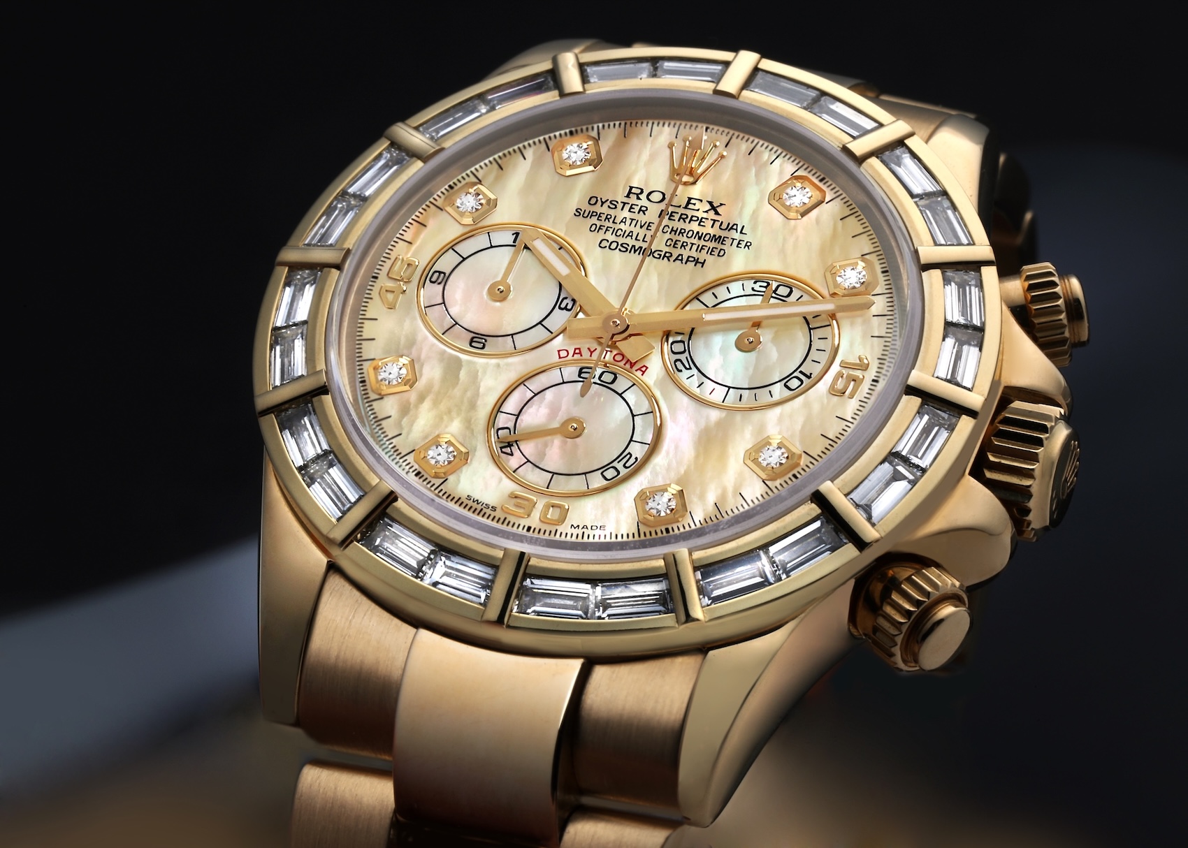 Macro view of a Rolex Cosmograph Daytona in 18k yellow gold featuring a factory-set baguette diamond bezel and white mother of pearl dial.