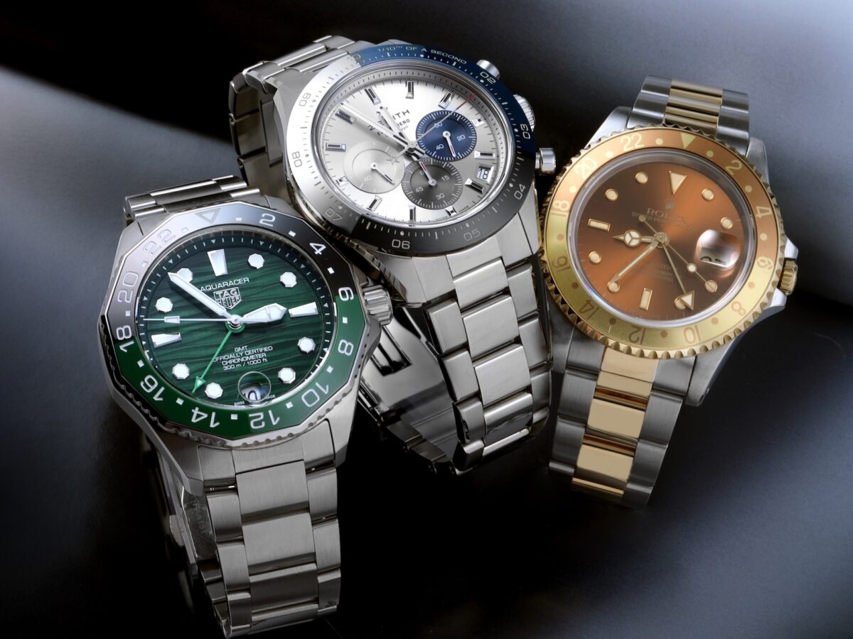 Group of three luxury mens watches featuring a green TAG Heuer Aquaracer, silver Zenith Chronomaster Sport, and two-tone Rolex GMT-Master II Root Beer.