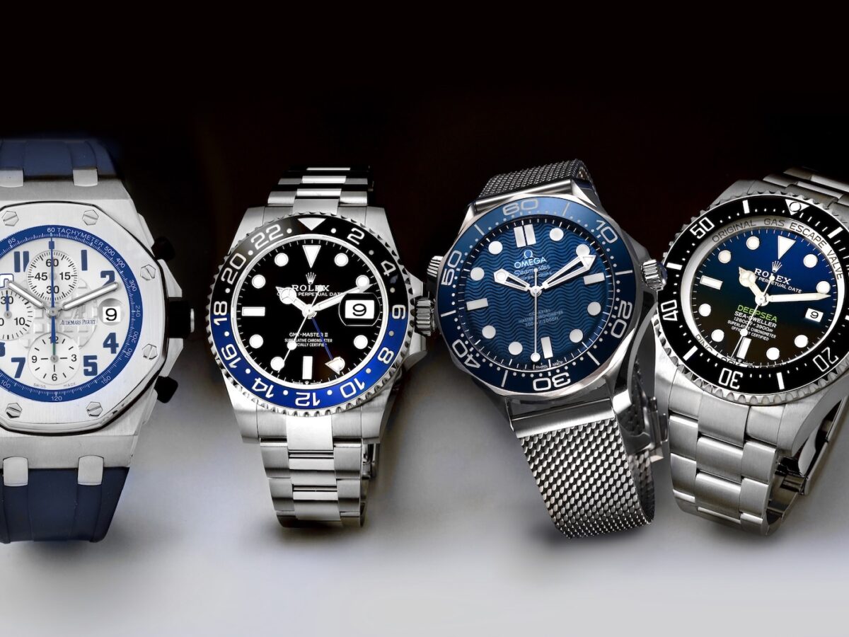A collection of four luxury mens sports watches including an Audemars Piguet Royal Oak Offshore, Rolex GMT-Master II Batman, Omega Seamaster, and Rolex Deepsea.