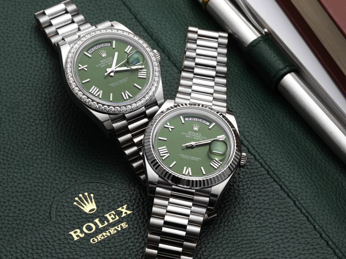 Two Rolex Day-Date President watches in white gold with green dials resting on a green leather pad, representing the luxury timepieces worn by elite World Cup football stars.