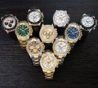A diverse collection of luxury Rolex Cosmograph Daytona watches in yellow gold, rose gold, and white gold displayed on a dark wooden surface.