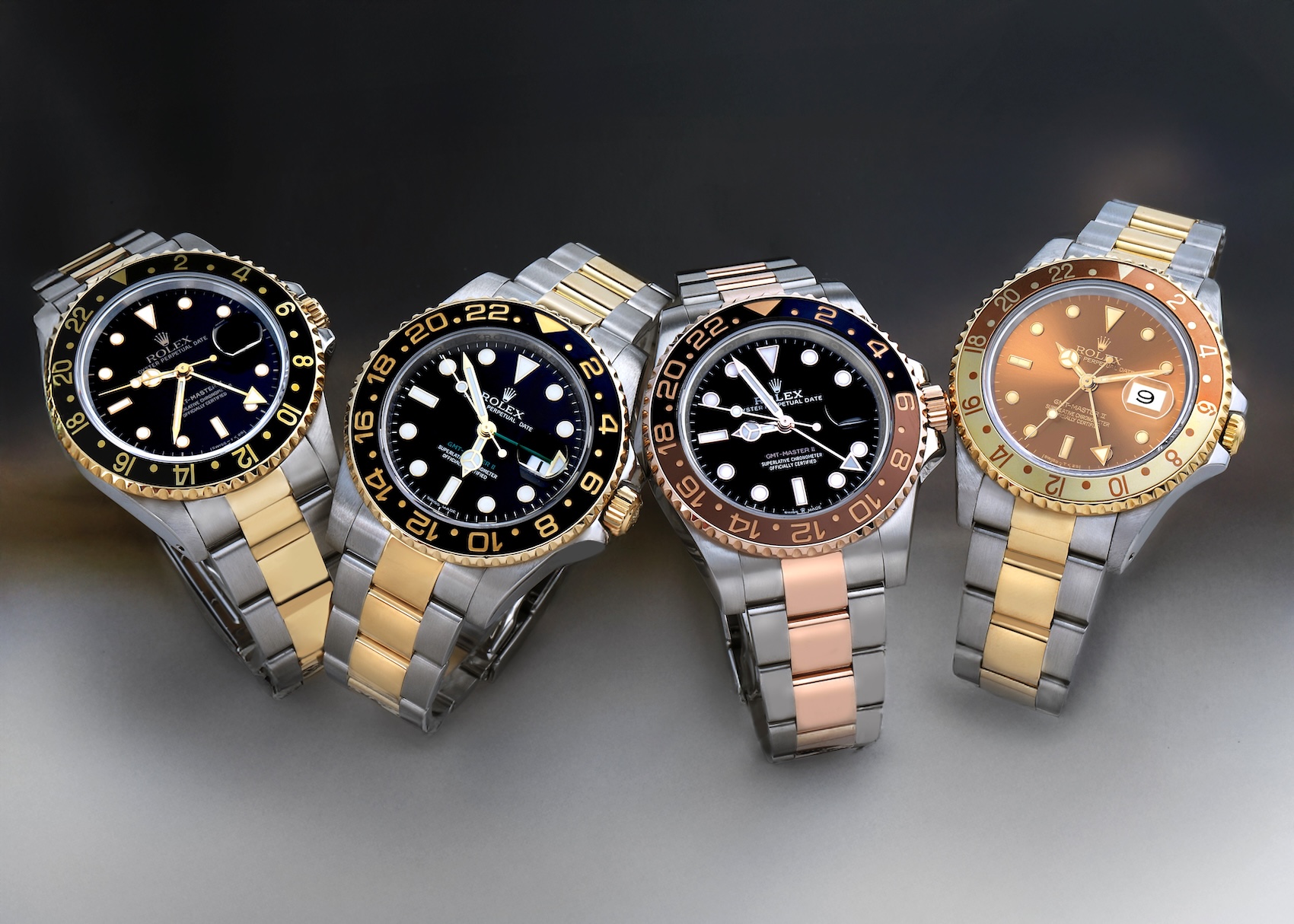 A side-by-side lineup of four different generations of two-tone Rolex GMT-Master II watches including references 16713, 116713LN, and 126711CHNR.