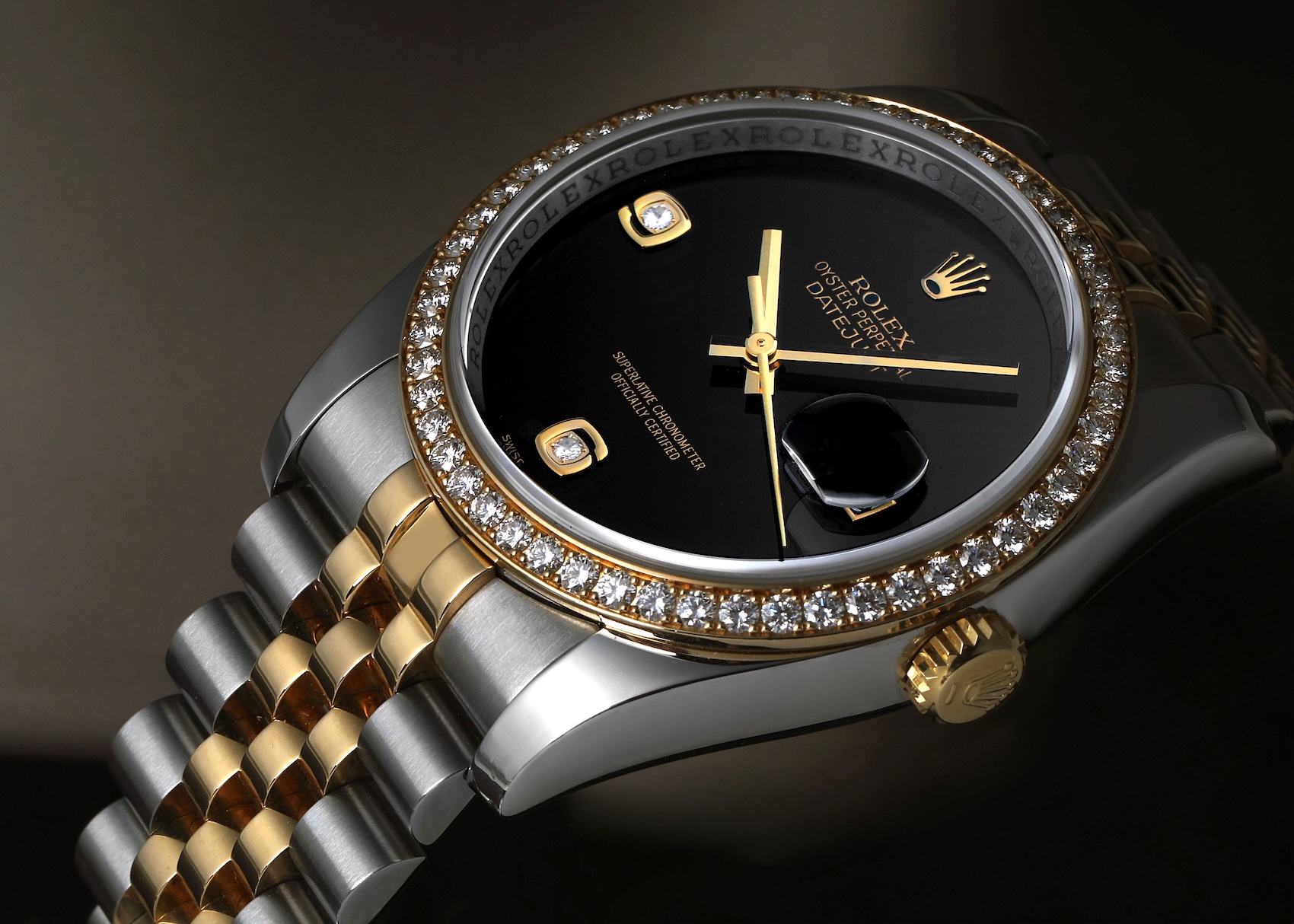 An angled studio shot of a two-tone steel and yellow gold Rolex Datejust 36 reference 116243 with a factory diamond bezel and a solid black onyx stone dial.