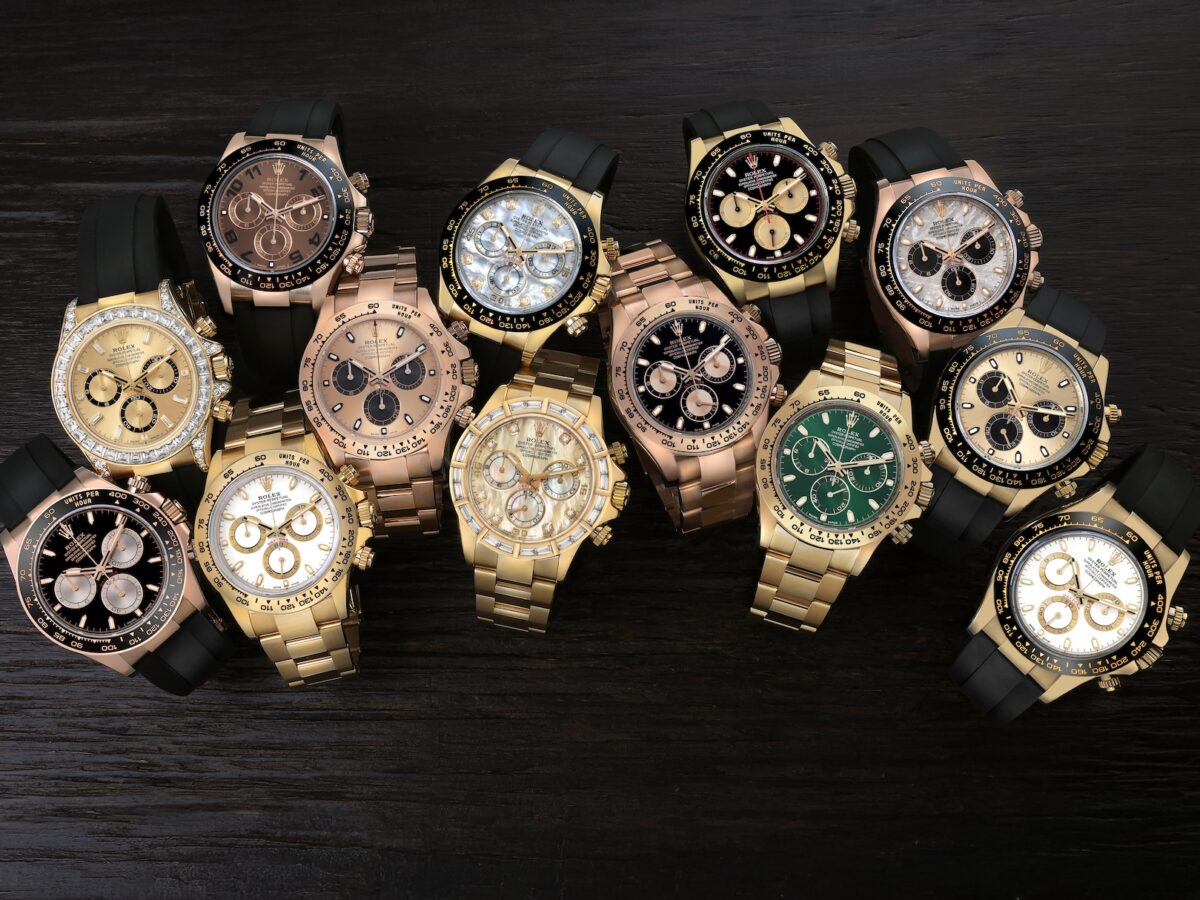 A high-contrast collection of luxury gold Rolex Daytona chronographs on black Oysterflex bracelets, featuring various dials.