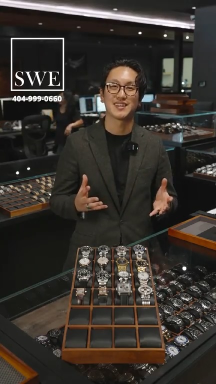 Host Jason stands behind a display of sixteen luxury watches at the start of the Top Quality Designer Watch Shop live Grail Bracket tournament.