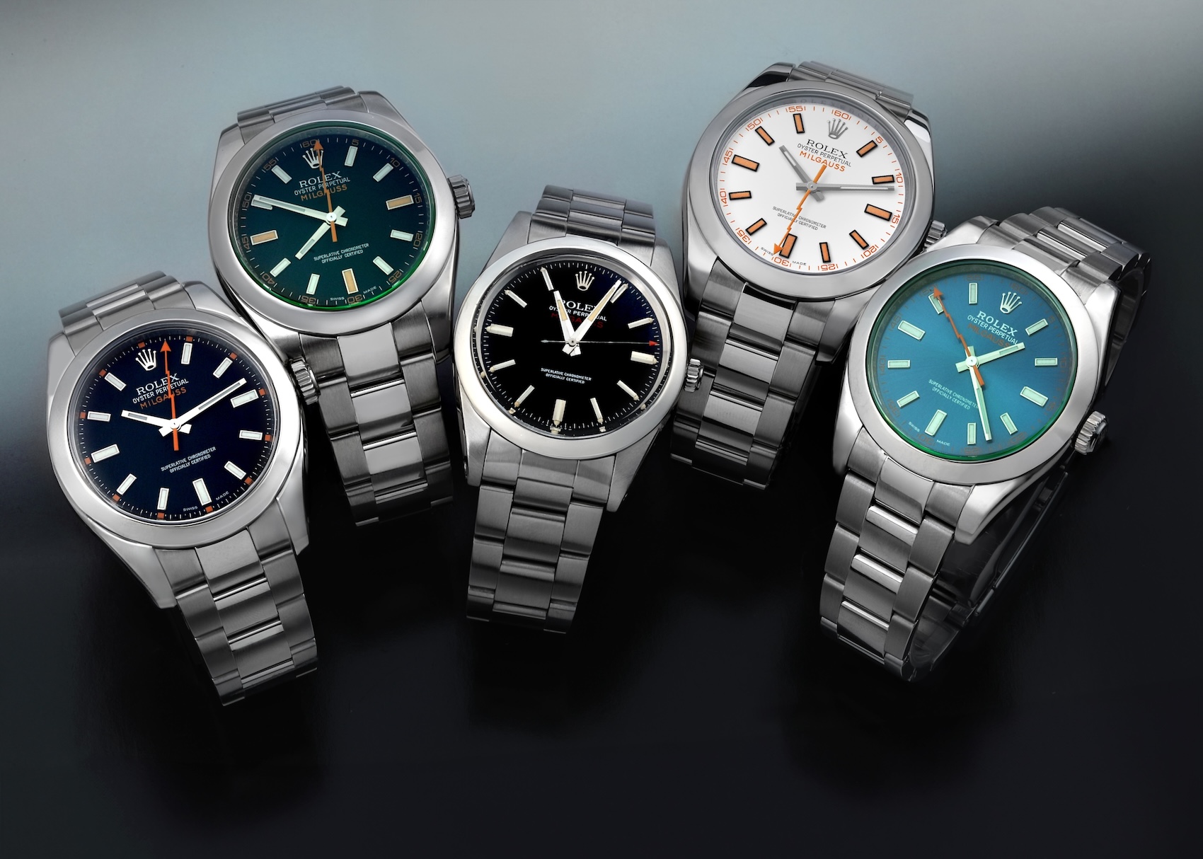 Collection of four discontinued Rolex Milgauss watches featuring green sapphire crystals and various dial colors including Z-Blue, white, and black.