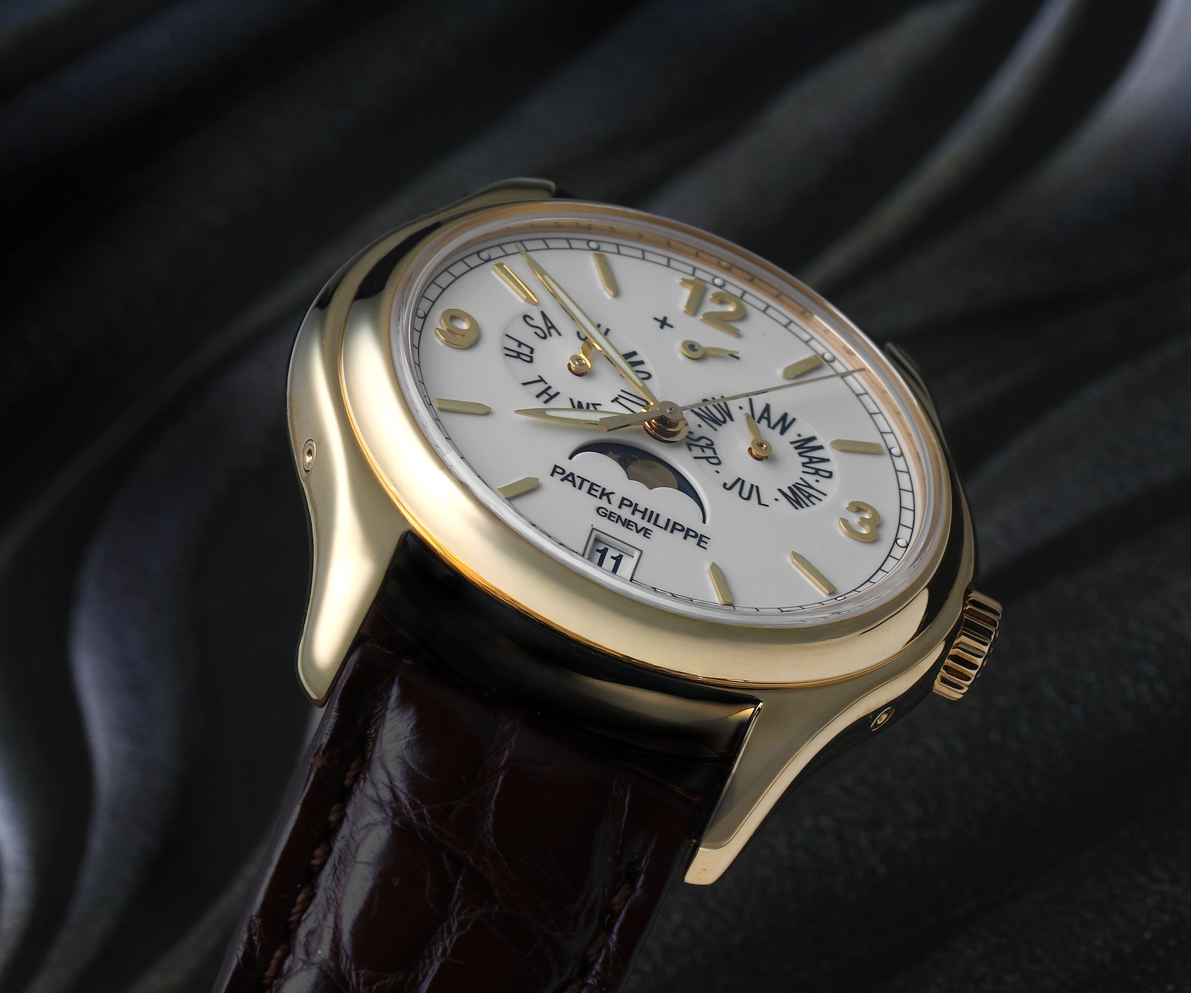 Close-up dial shot of the Patek Philippe 5146J showing luminous leaf hands, a 12 o'clock power reserve indicator, and moonphase display.