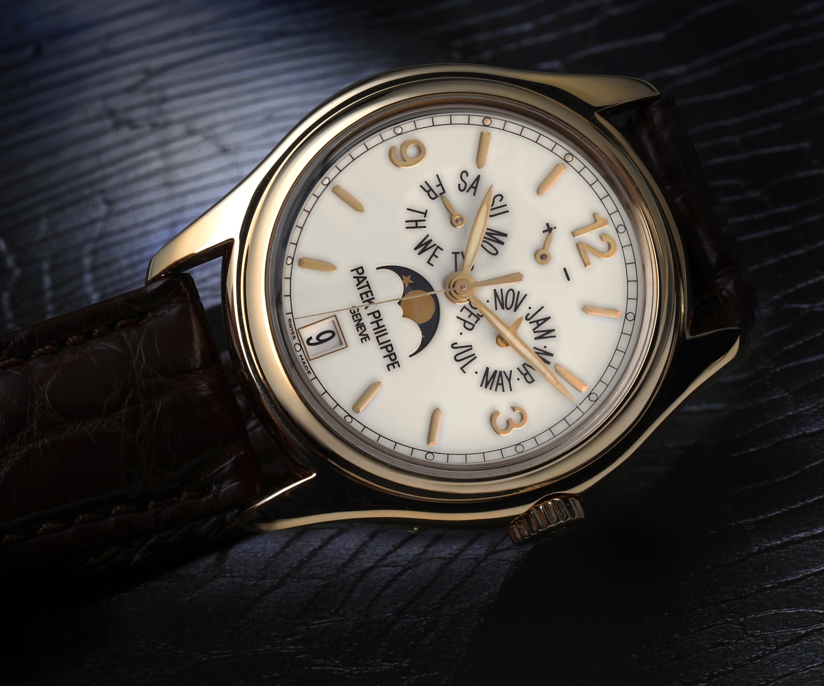 Angled profile of the Patek Philippe 5146J case in yellow gold on a dark brown alligator leather strap, highlighting the calendar correctors.