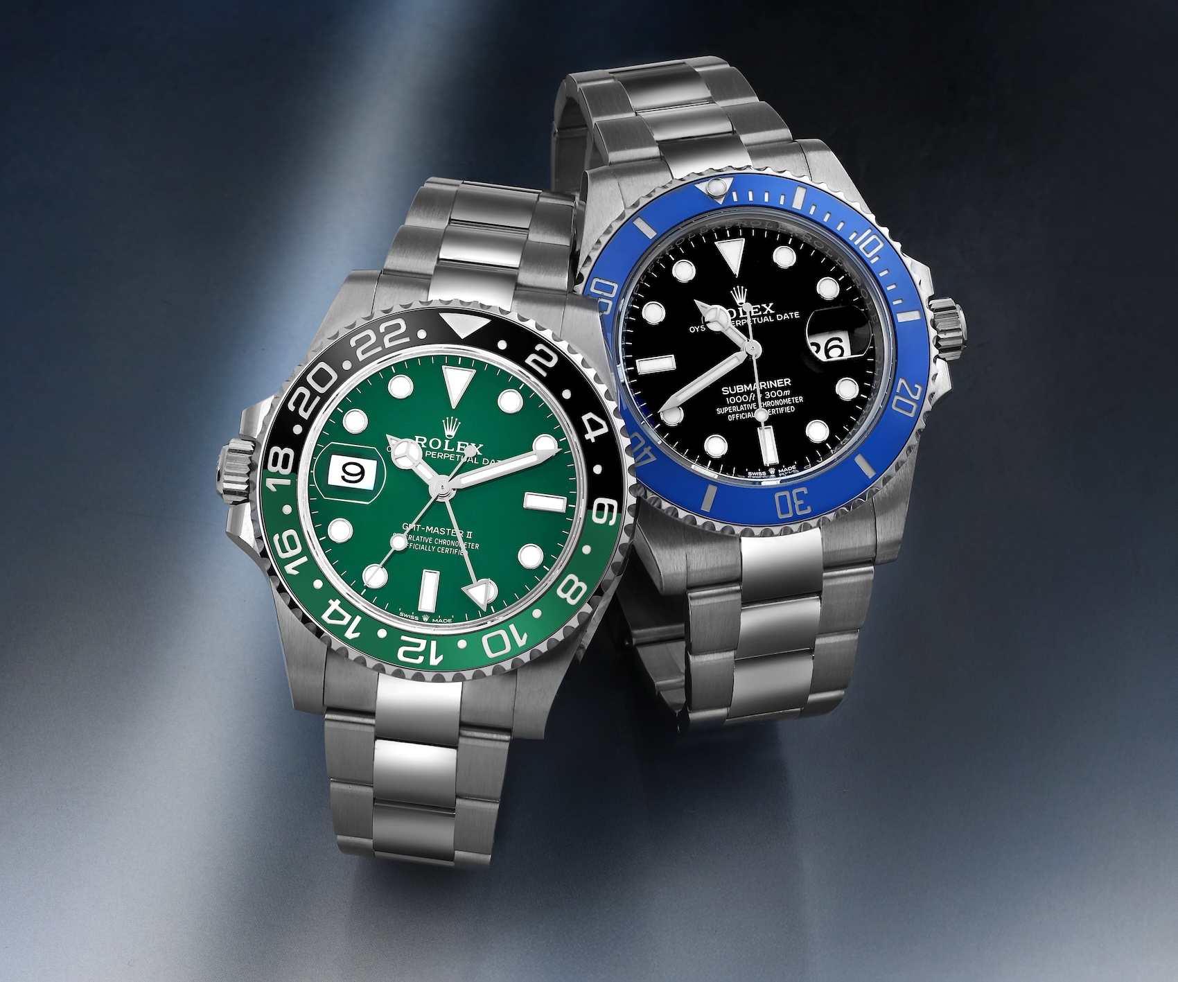 A perspective shot of two current Rolex sports watches angled toward each other: on the left, the left-handed green-bezel "Sprite" GMT-Master II (126720VTNR), and on the right, the blue-bezel "Cookie Monster" Submariner (126619LB), highlighting their distinct aesthetics and configurations.
