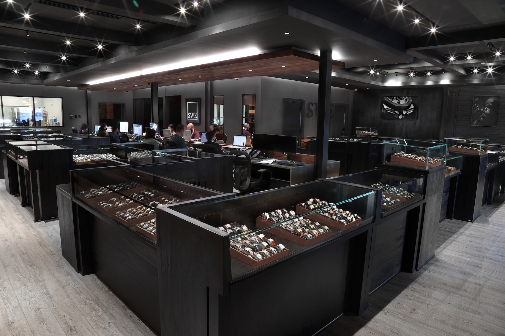 The Top Quality Designer Watch Shop showroom in Atlanta displaying hundreds of authenticated luxury watches in illuminated glass cases.