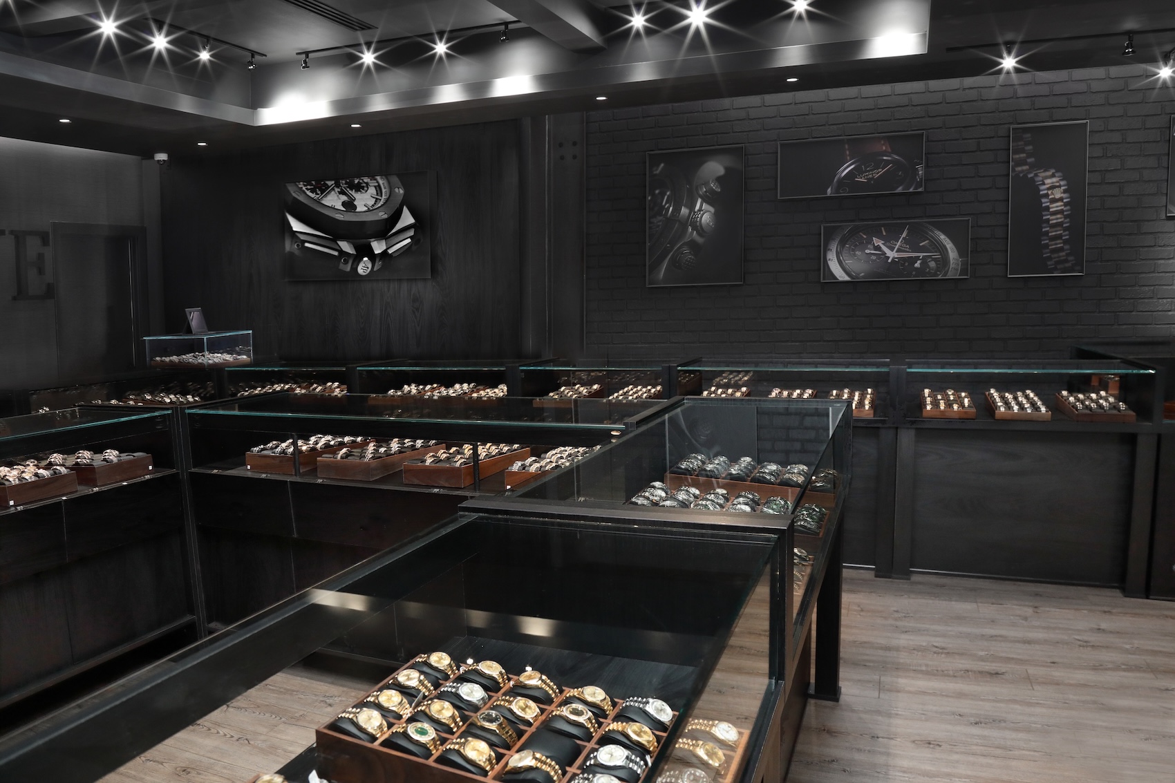 The interior of the Top Quality Designer Watch Shop showroom featuring rows of illuminated glass display cases filled with authenticated pre-owned luxury watches.